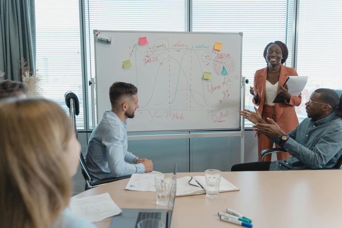 Multicultural team discussing strategies in a conference room with a whiteboard presentation.