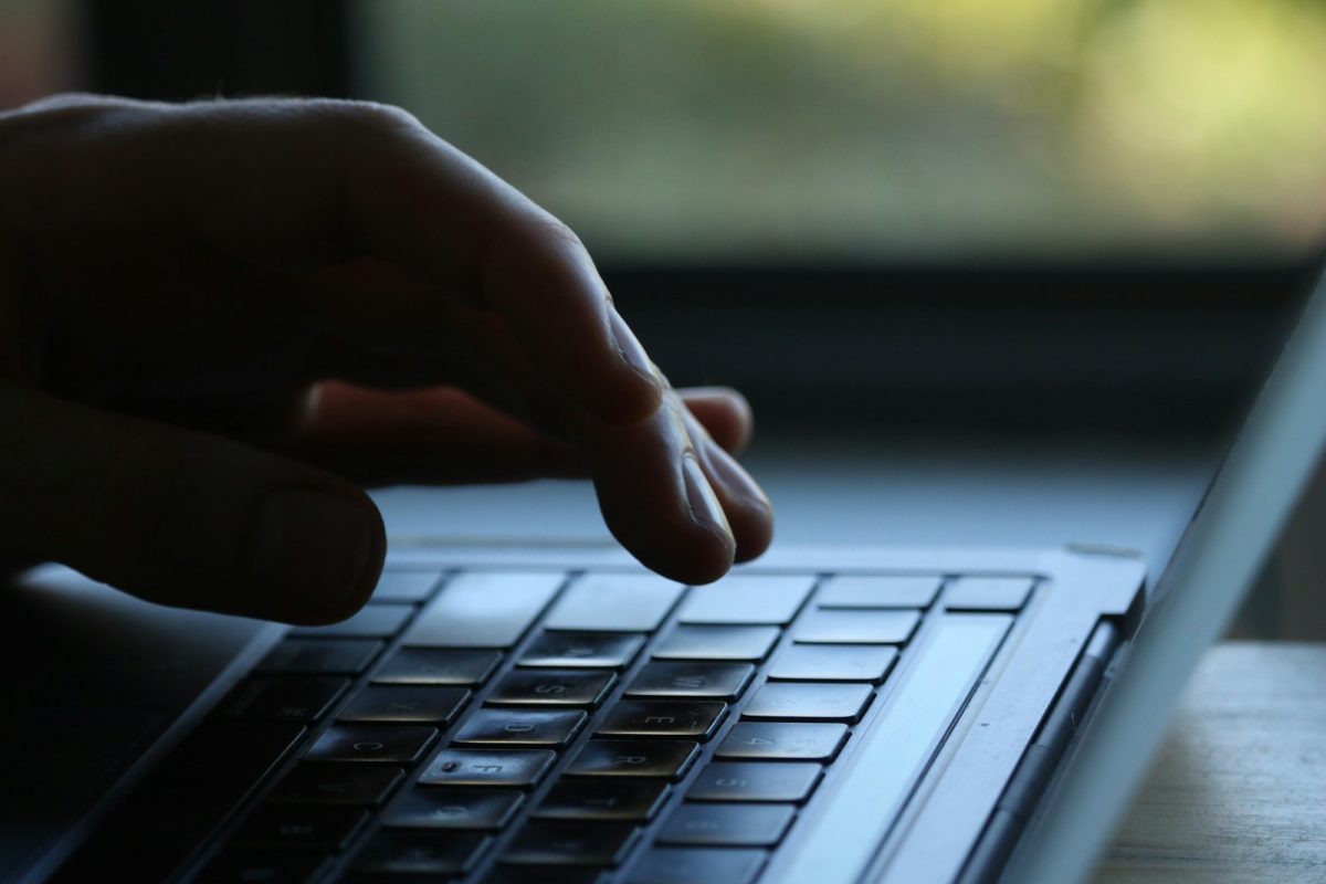 A hand typing on a laptop keyboard