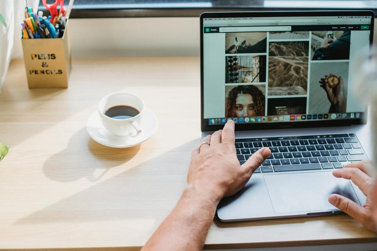 Osoba koristi laptop i pregleda sadržaj na web sajtu uz šolju kafe – ilustracija za hosting za sajt uptime i stabilan rad online platforme.