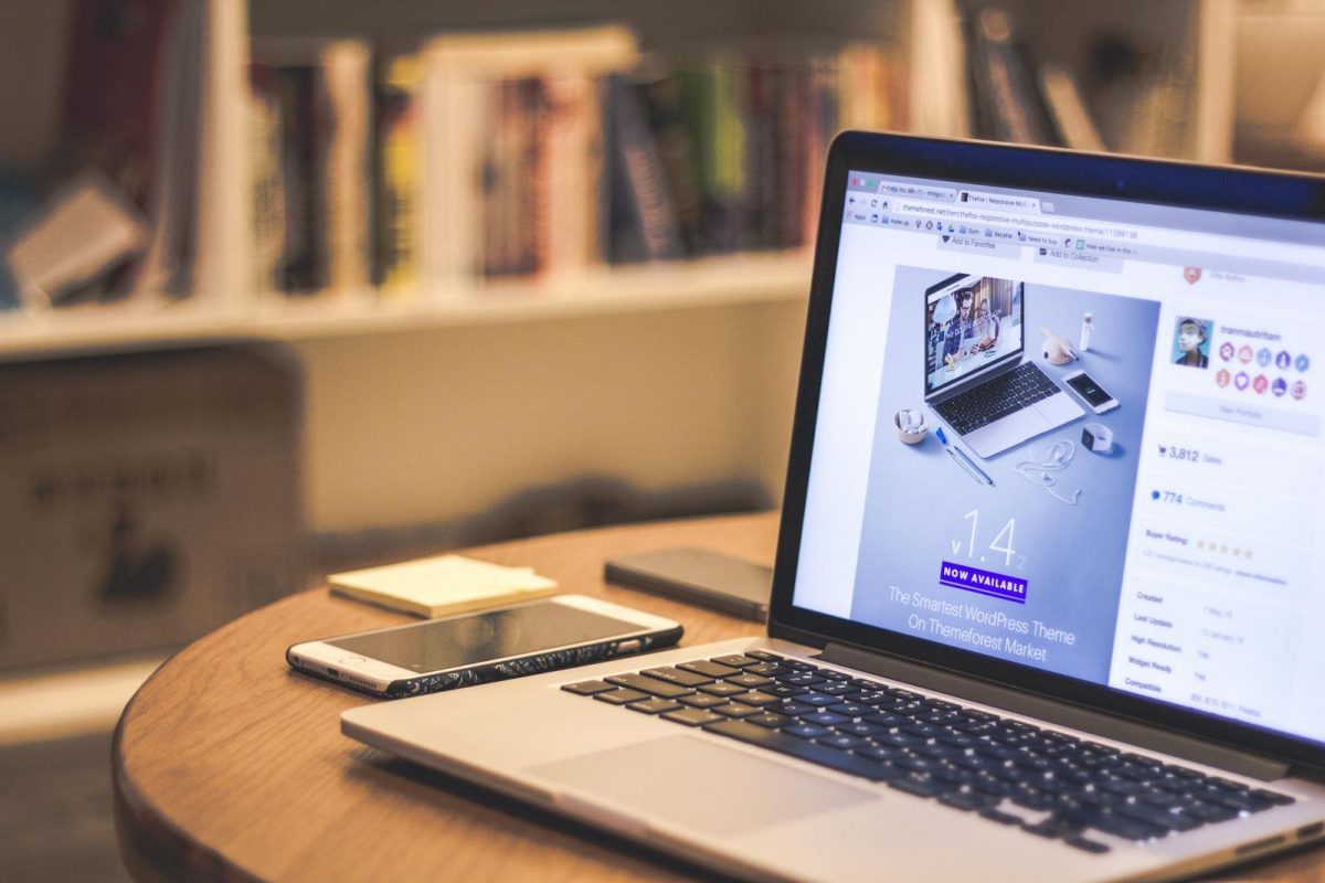 Laptop na stolu sa prikazom ilustracija za hosting i upravljanje web sadržajem u modernom radnom okruženju.